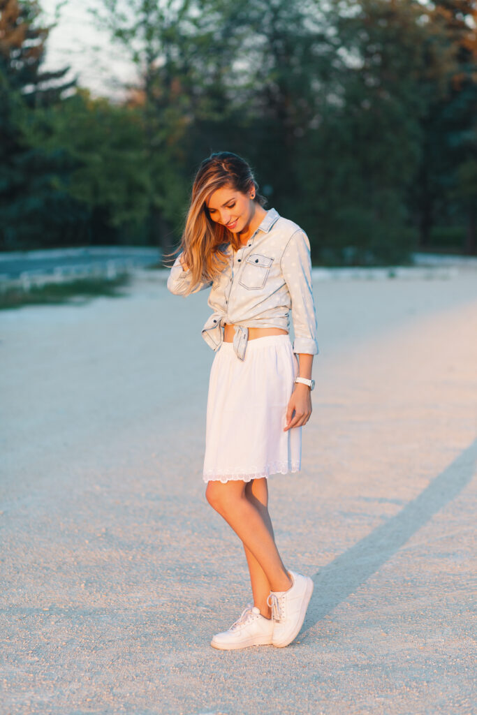 White sneakers with a white skirt and denim shirt